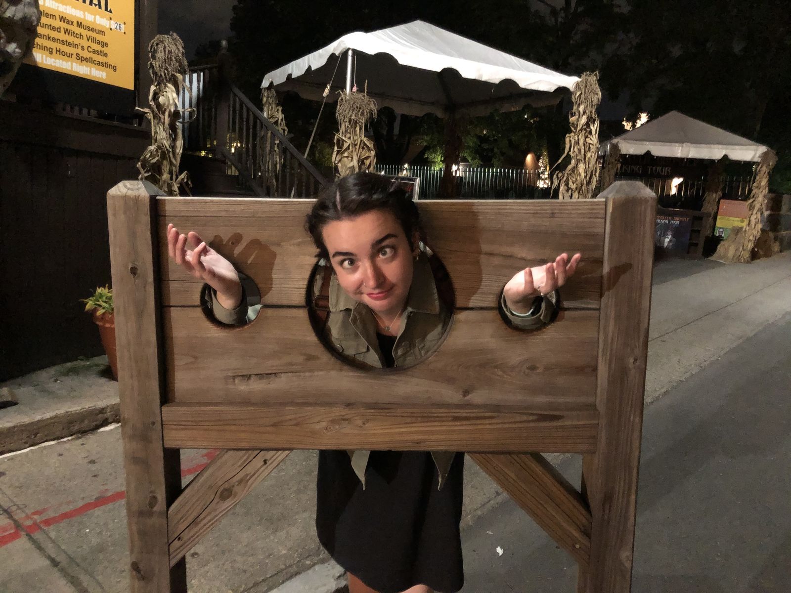 Leigh-Anne pulling a funny face with her head and hands locked in old wooden stocks at night